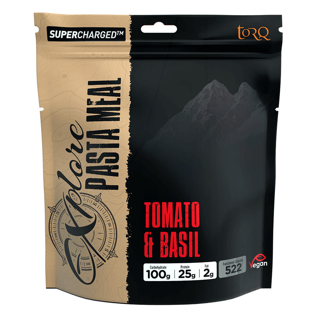 A stand-up pouch of Torq Supercharged Pasta Meal in Tomato & Basil flavor. The packaging features a split design with a beige/tan textured left side and a black right side showing a mountain graphic, with red text indicating the flavor.